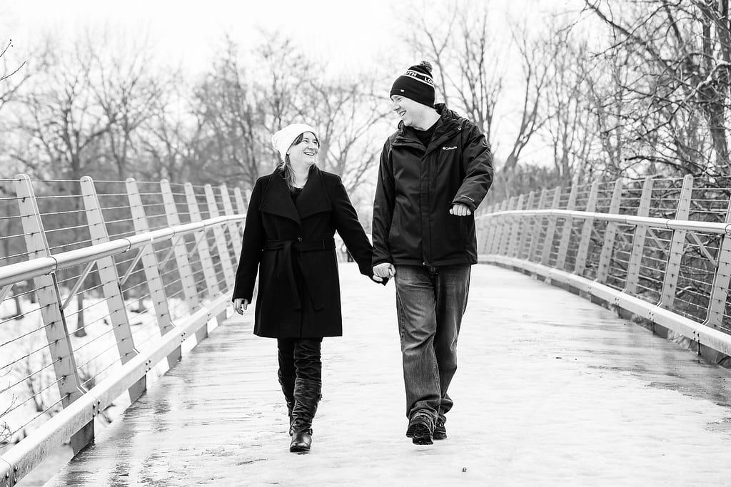 couple walking on bridge Winter engagement photos London Ontario